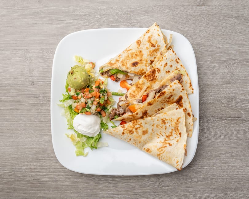 Steak quesadillas with bell peppers and onions, served with guacamole, pico de gallo, and sour cream.